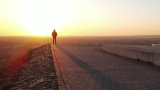 Michael Raser steht vor der untergehenden Sonne