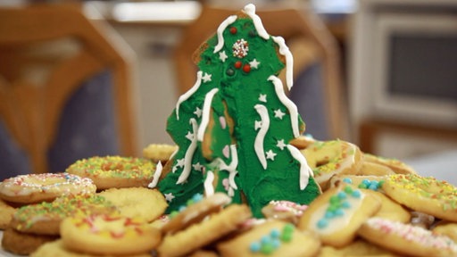 Weihnachtsplätzchen mit Streuseln auf einem Teller, in der Mitte ein Bäumchen aus Plätzchen mit grünem Zuckerguss