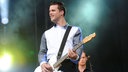 Der Gitarrist der "White Lies" spielt auf den Saiten seiner Gitarre und blickt zur Seite