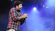 Der Sänger der Band Deftones umklammert das Mikrofon, hat seine Augen fest geschlossen und singt angestrengt