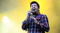 Deftones-Bandmitglied singt mit zusammengekniffenen Augen vor einem gelben Hintergrund 