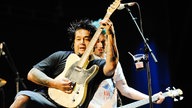 Gitarrist von Nofx hält sein Instrument nach oben und lehnt sich zurück