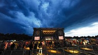 Über der Bühne des Festivals braut sich ein Gewitter zusammen. Dem Andrang vor der Bühne tut das keinen Abbruch