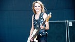 Bassistin von The Subways spielt und schaut entspannt in die Kamera