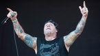 Tatoowierter Sänger von Agnostic Front hebt die Hände und zeigt auf das Publikum