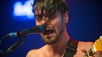 Einer der Sänger von Biffy Clyro singt mit fest geschlossenen Augen in sein Mikrofon.