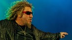 Sammy Hagar mit gespitzten Lippen und dem linken Arm zur Seite gestreckt