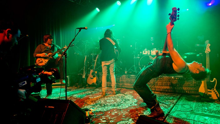 Bühnenkulisse beim Konzert von Brother & Bones. Rechts im Bild lehnt sich der Bassist beim spielen sehr weit zurück.