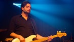 Bassist spielt mit geschlossenen Augen im blauen Bühnenlicht