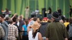 Rückansicht von zwei Festivalbesuchern, eine Frau mit Stroh- und ein Mann mit Cowboyhut. 