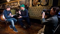 Manuel Unger im Interview mit Jake Bugg, der seine Gitarre hält.