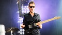 The Editors Frontmann Tom Smith hält die Gitarre mit beiden Händen fest