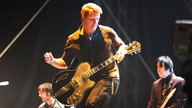 Die Queens Of The Stone Age peformen zusammen zu dritt auf der Bühne 