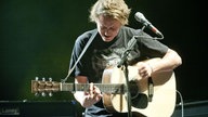 Ben Howard spielt konzentriert auf der Akkustik-Gitarre