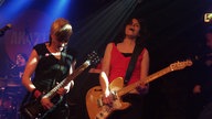 Die beiden Frauen an den Saiteninstrumenten stehen im Vordergrund bei Bootleg im April 2006 während im Hintergrund die Schlagezugerin am Mikrofon mitsingt.