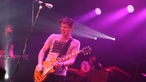 Jonny Lang in pinkem Licht beim Gitarre spielen