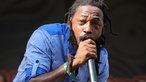  Lutan Fyah mit MIkrofon in blau kariertem Hemd