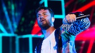 Marteria in einer bunt gemusterten Jacke, die perfekt zur fluoreszierenden Bühnendeko passt.