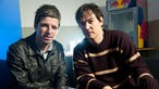 Noel Gallagher sitzt mit Rockpalast-Moderator Ingo Schmoll auf der Couch.