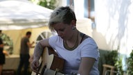 Rah Rah spielt einen Unplugged Song, junge Frau spielt Gitarre