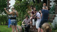 Die Band Keston Cobblers' Club sitzt auf einer Treppe und spielt unter freiem Himmel einen ihrer Songs Unplugged für das Rockpalast Team, welches die Szene Filmt