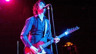 Sänger von "The Jon Spencer Blues Explosion" steht auf der Bühne und singt