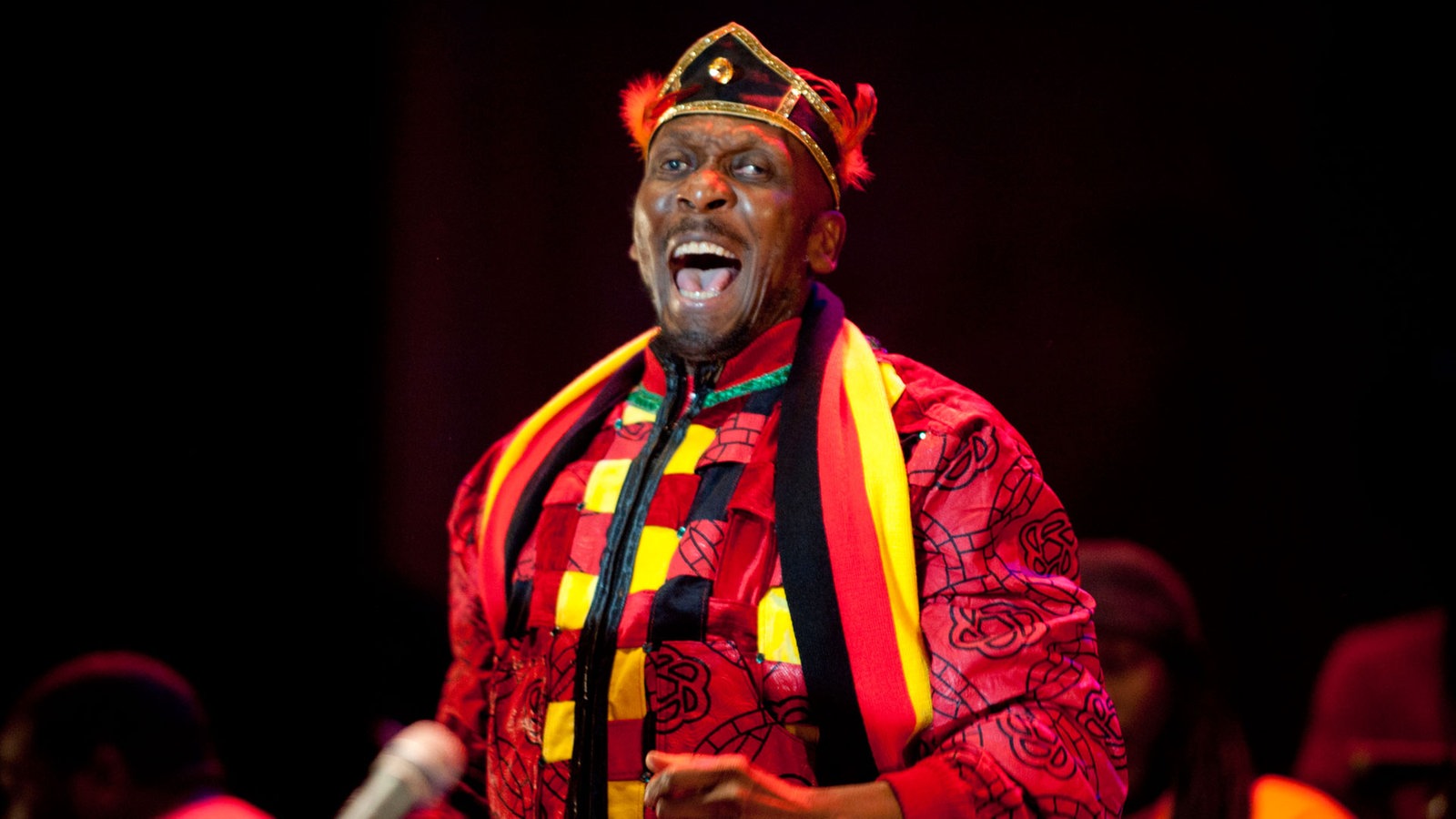 Jimmy Cliff trägt einen Deutschland-Schal um den Hals und singt dabei mit weit aufgerissenem Mund