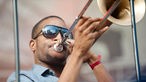 Der Trompeter Trombone Shorty trägt eine Sonnenbrille und spielt seine Posaune 