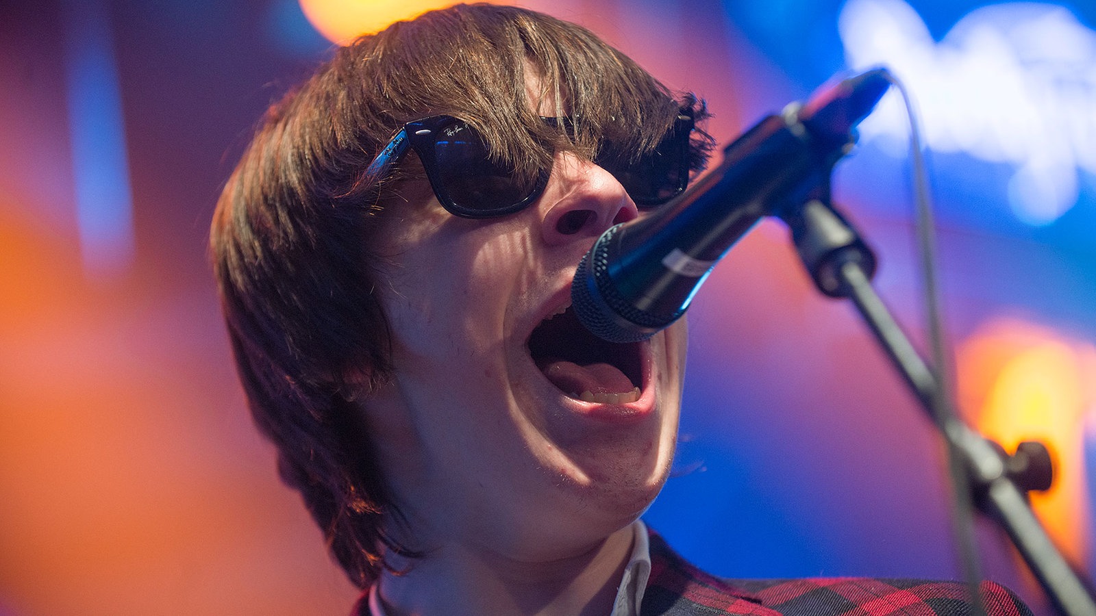 The Strypes-Sänger Ross Farrelly mit Wayfarer-Sonnenbrille am Mikrofon.