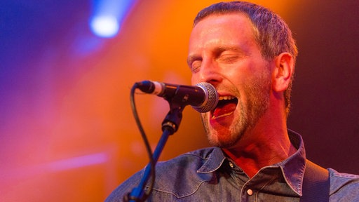 Pete MacLeod singt mit geschlossenen Augen und Schweiß auf der Stirn.