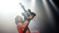 Truckfighters Gitarrist hält seine Gitarre in die Luft.