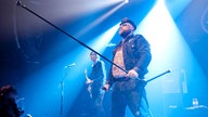 Der Sänger von Turbonegro hält den Mikrofon Ständer wie eine Lanze vor sich in Richtung des Publikums.