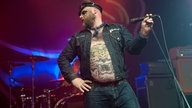 Der Sänger von Turbonegro steht mit dem Publikum abgewandtem Gesicht auf der Bühne.