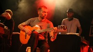 Don Philippe vom Freundeskreis spielt im Sitzen auf seiner Gitarre beim Underground Festival 2007