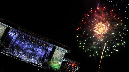 Links auf der Bühne haben Heaven Shall Burn ihr Konzert beendet, rechts startet ein Schamane sein Feuerwerk