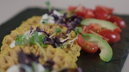 Das Bild zeigt zeigt Linsenwaffeln mit Tomaten Avocado Salat.