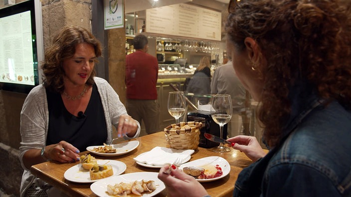 Anne Willmes und eine weitere Frau sitzen in einer Bar an einem Tisch mit mehreren Tellern