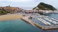 Bucht mit Sandstrand, Yachthafen, einer Klippe und einem Ort