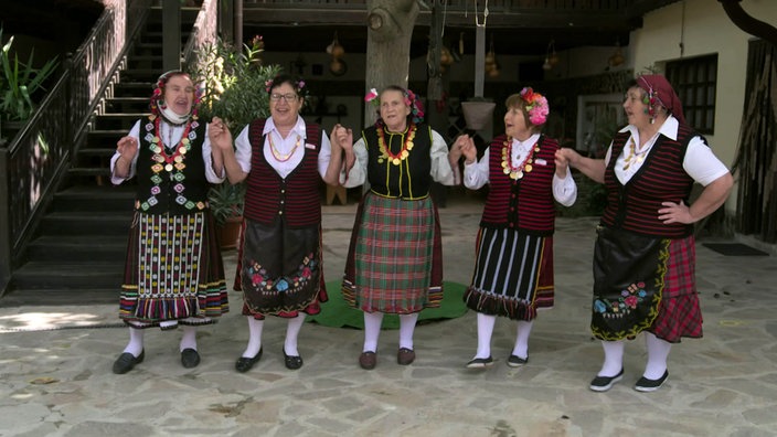 Fünf ältere Damen in traditioneller Tracht tanzen in einer Reihe 