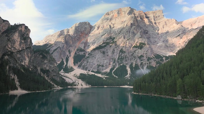 Kleiner Bergsee zwischen teils bewaldeten und teils sehr felsigen Bergen