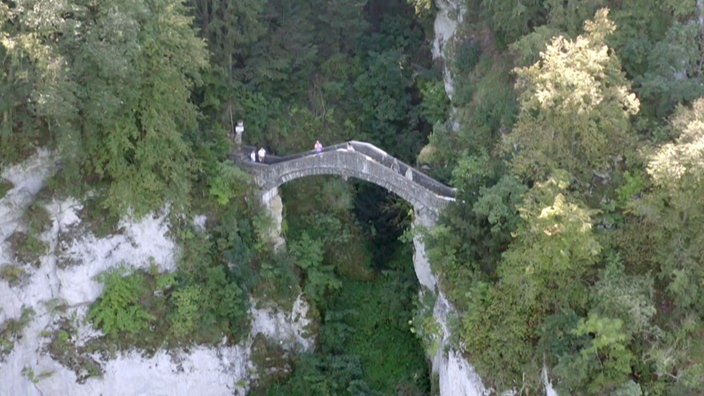 Schmale Natursteinbrücke über einem tiefen Felsental