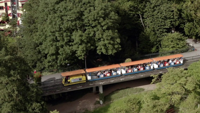 Touristenbahn mit drei Waggons fährt durch eine Parkanlage