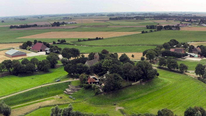 Kleine bewaldete Anhöhe mit einer Kirche in der ansonsten flachen Landschaft