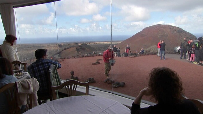 Gäste schauen aus einem Restaurant auf karge Mondlandschaft