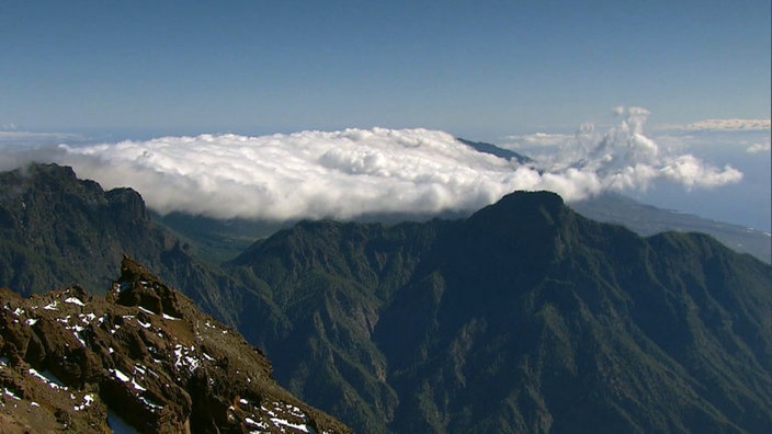 Blick von einem Berg auf andere, wolkenumkränzte Berggipfel