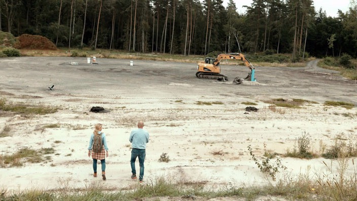 Sprengstoffexperte Carsten Bubke geht mit Judith Rakers zum Dethlinger Teich, in dem in den 1940er-Jahren Sprengstoffe und chemische Kampfstoffe verklappt wurden.