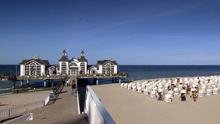 Blick auf Sandstrand mit Strandkörben und auf die Seebrücke