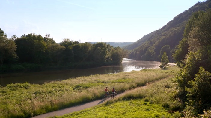 Blick von oben auf die Ruhr, neben der Anne Willmes und Stefan Pinnow auf dem Radweg fahren