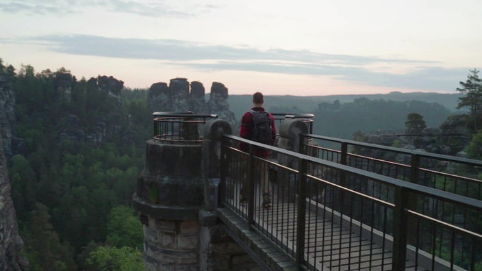 Ramon Babazadeh steht auf einem Aussichtspunkt und schaut auf die  Felsen der Bastei