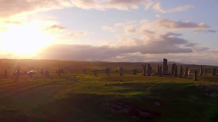 Tiefstehende Sonne über einer Landschaft mit vielen aufrecht stehenden Felsbrocken in einer Reihe